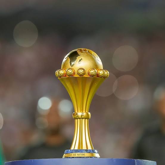 The AFCON trophy in front of a blurred stadium