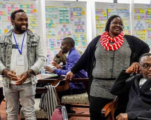 Participants at a creative workshop standing and talking in front of walls covered in sticky notes