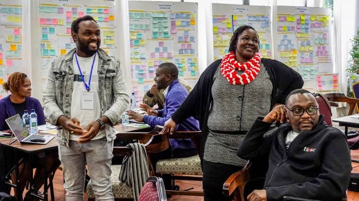 Participants at a creative workshop standing and talking in front of walls covered in sticky notes