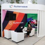 Flutterwave exhibition booth with colourful striped panels and people talking in white armchairs