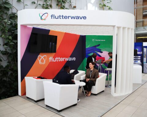 Flutterwave exhibition booth with colourful striped panels and people talking in white armchairs