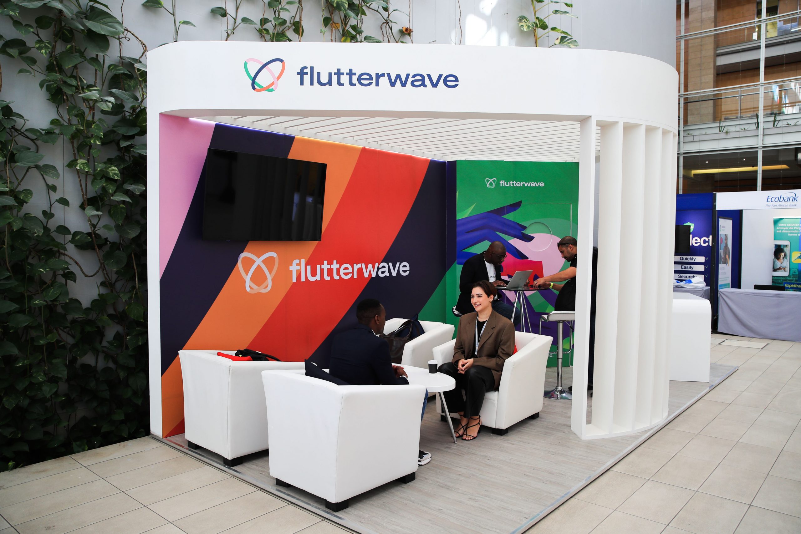 Flutterwave exhibition booth with colourful striped panels and people talking in white armchairs