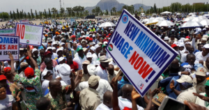 Workers at a Nigeria Labour Congress rally in Abuja holding a sign that reads New Minimum Wage Now