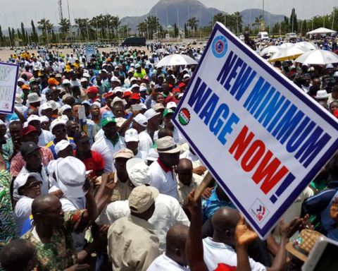 Workers at a Nigeria Labour Congress rally in Abuja holding a sign that reads New Minimum Wage Now