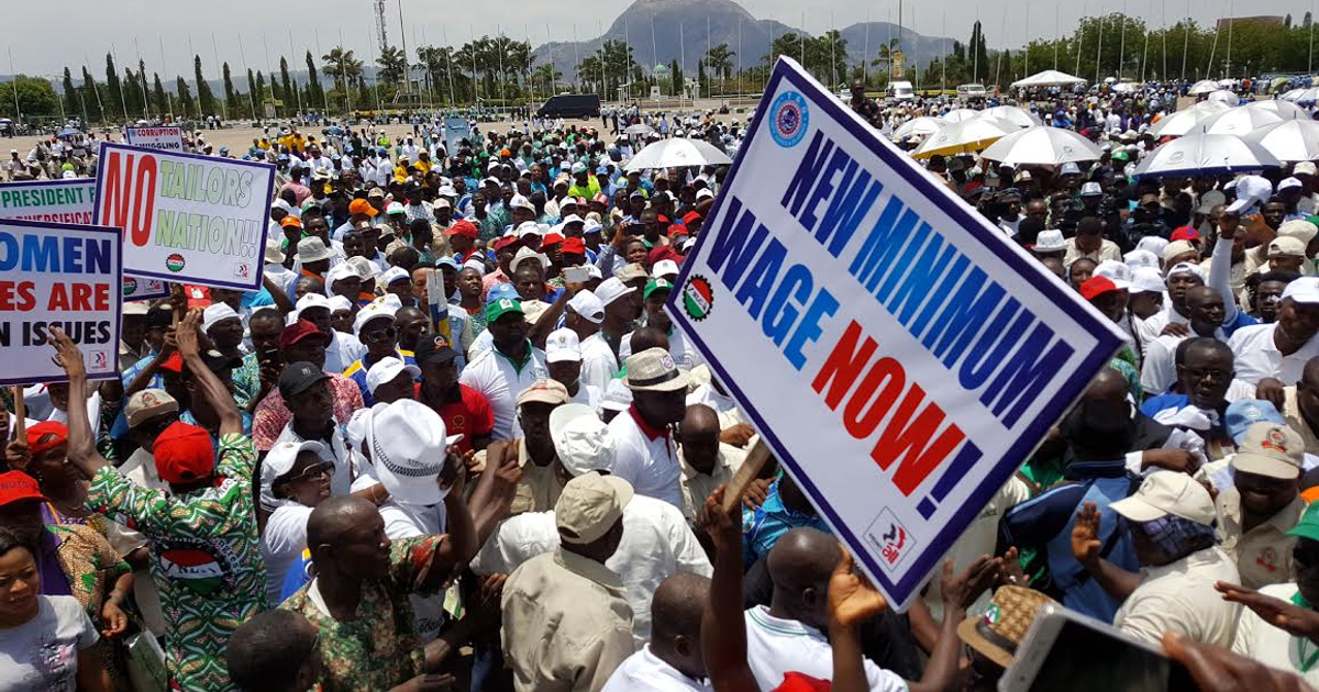 Workers at a Nigeria Labour Congress rally in Abuja holding a sign that reads New Minimum Wage Now