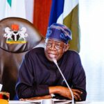 President Bola Tinubu speaking at a desk with the presidential seal on the chair behind him